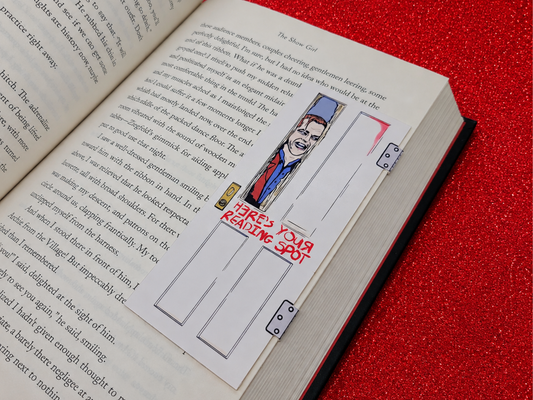 A magnetic bookmark inspired by Jack Torrance featuring him breaking through the wooden bathroom door with an axe. The words on the door read, "Here's your reading spot!"