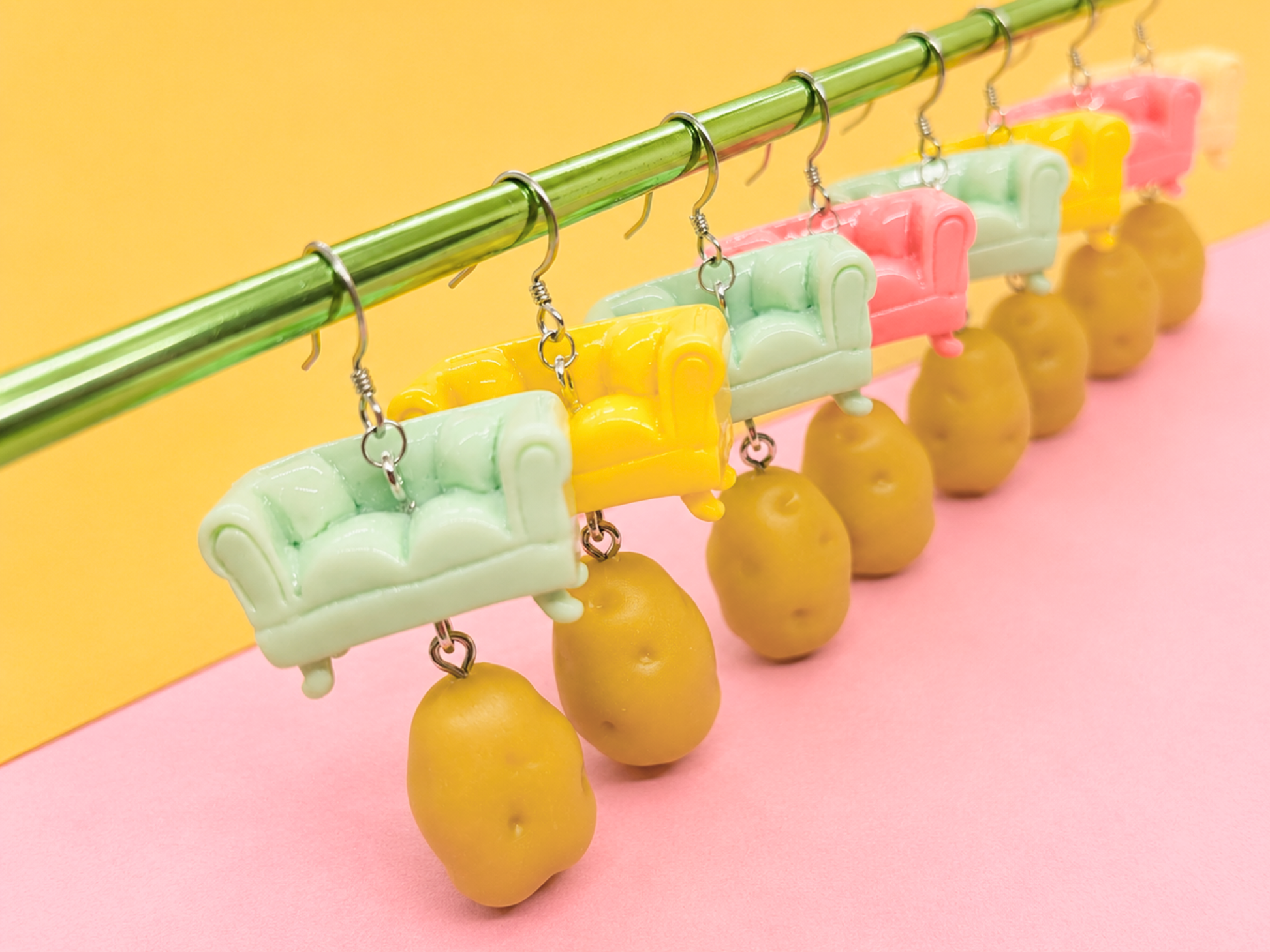 Several pairs of handmade Couch Potato earrings featuring couch charms with miniature potatoes dangling underneath.