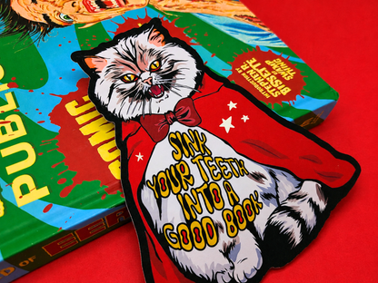 A close-up shot of a double-sided, die-cut bookmark featuring a Pallas Cat vampire wearing a red cape and bowtie.