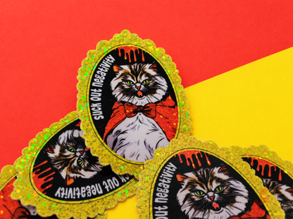 A close-up shot of the vampire Pallas cat glitter stickers resting on red and yellow cardstock.