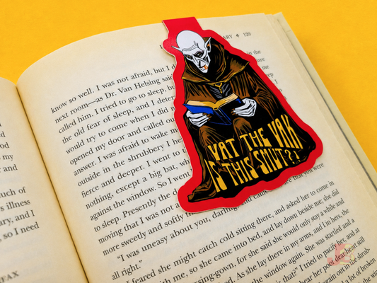 A Nosferatu magnetic bookmark securely clipped over the top of the pages of an open book.