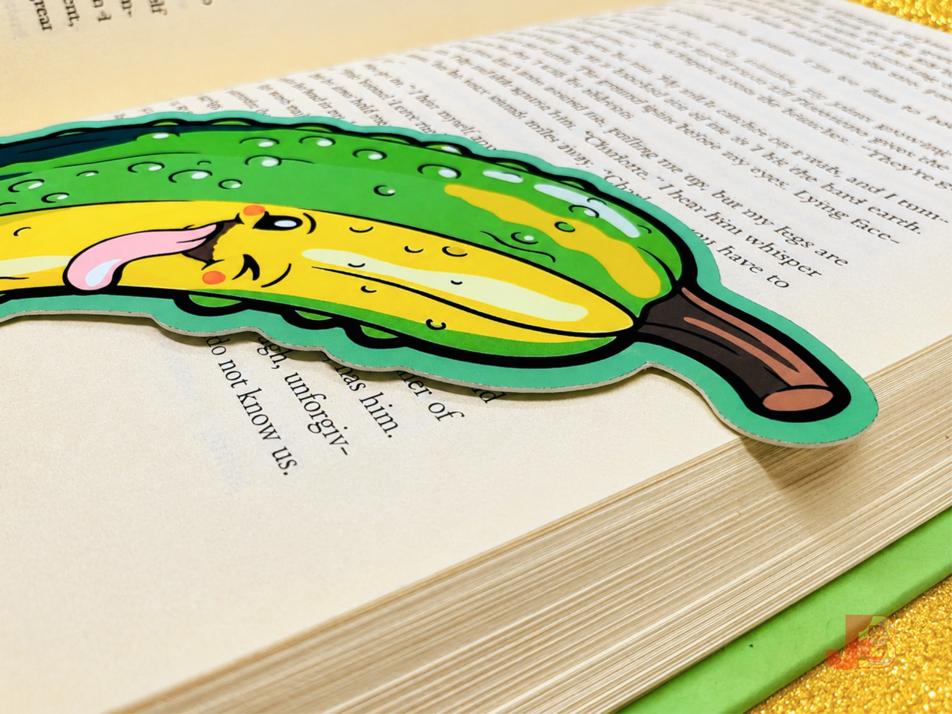 Up-close shot of the winking pickle bookmark resting on an open hardcover book.