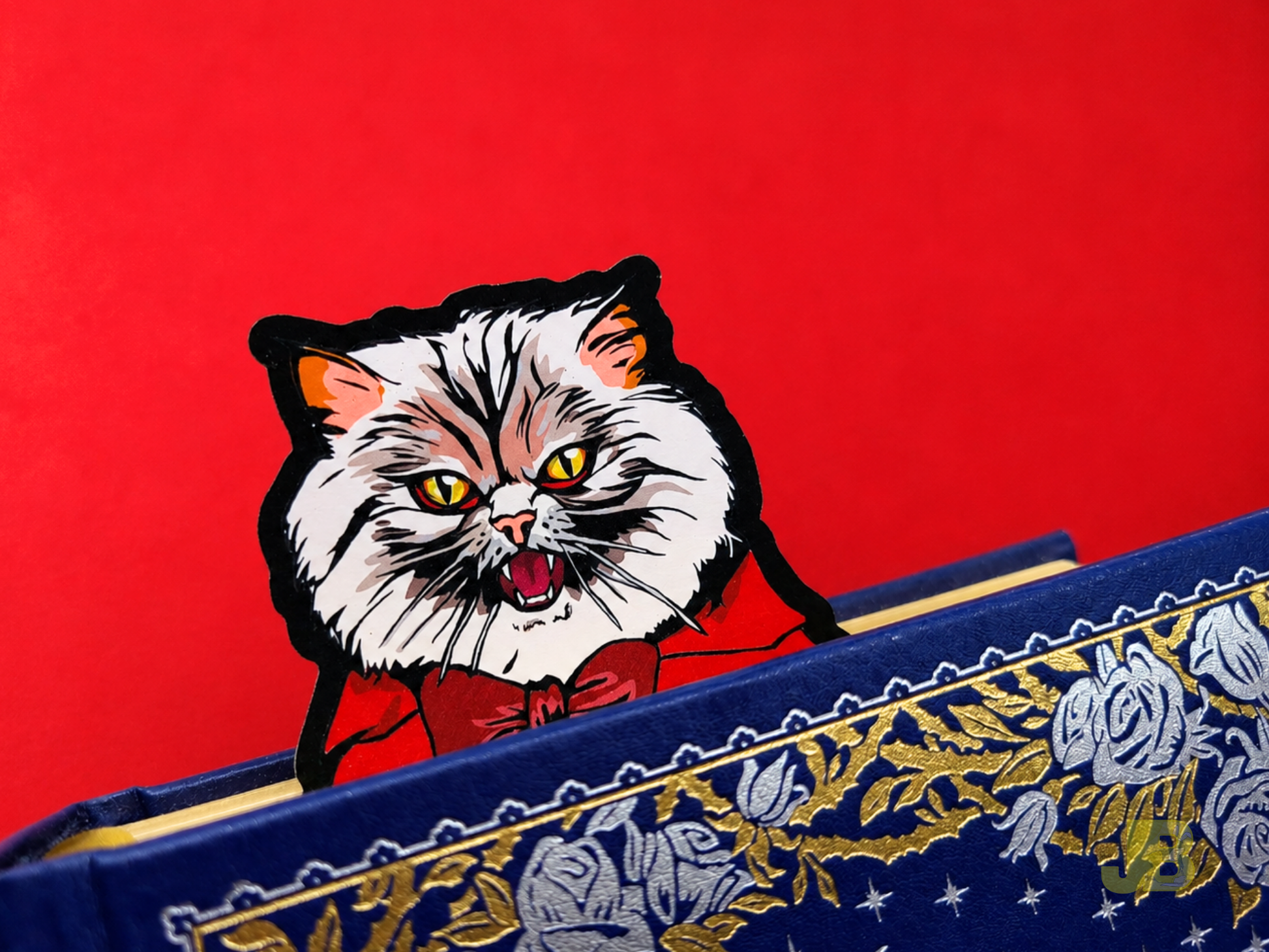 A Count Pallas vampire cat bookmark peeking out from the top pages a thick hardcover book. It features a Pallas Cat with fangs and a grumpy expression. Perfect for dark academia and romantasy readers.