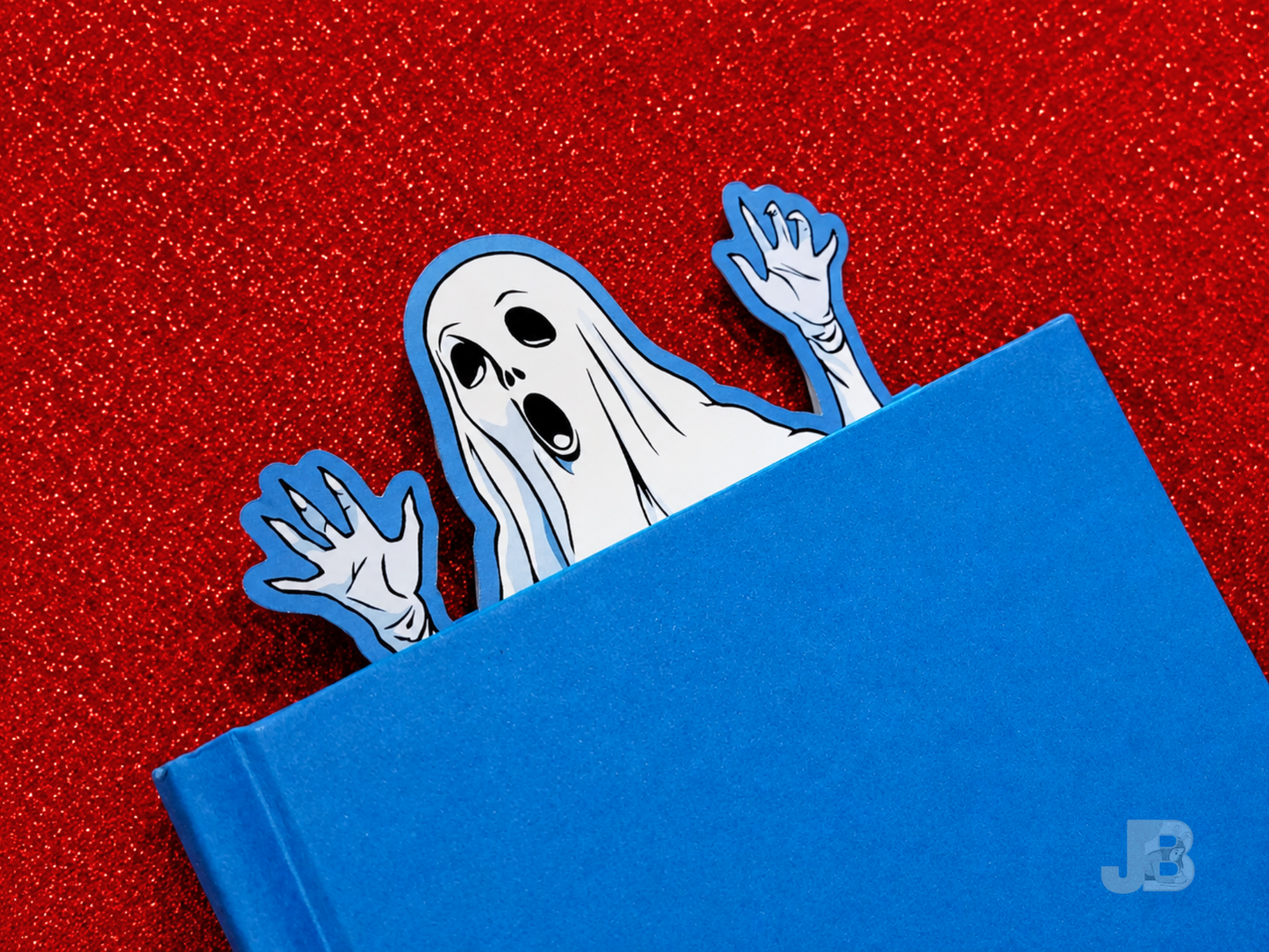 A lifestyle photo of the extra-large 7-inch ghost bookmark peeking out from the top pages of thick, hardcover novel.