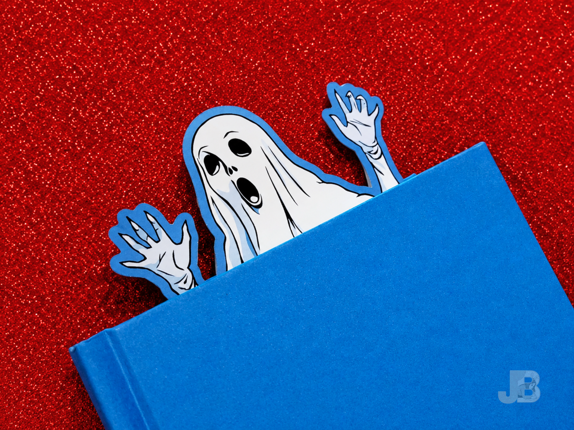 A lifestyle photo of the extra-large 7-inch ghost bookmark peeking out from the top pages of thick, hardcover novel.