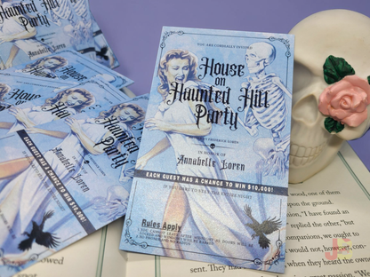 House on Haunted Hill invitation bookmarks resting on top of a novel, showcasing the authentic mid-century spooky typography and vintage party details.