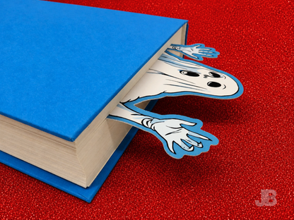 A lifestyle photo of the extra-large 7-inch ghost bookmark peeking out from the top pages of thick, hardcover novel.