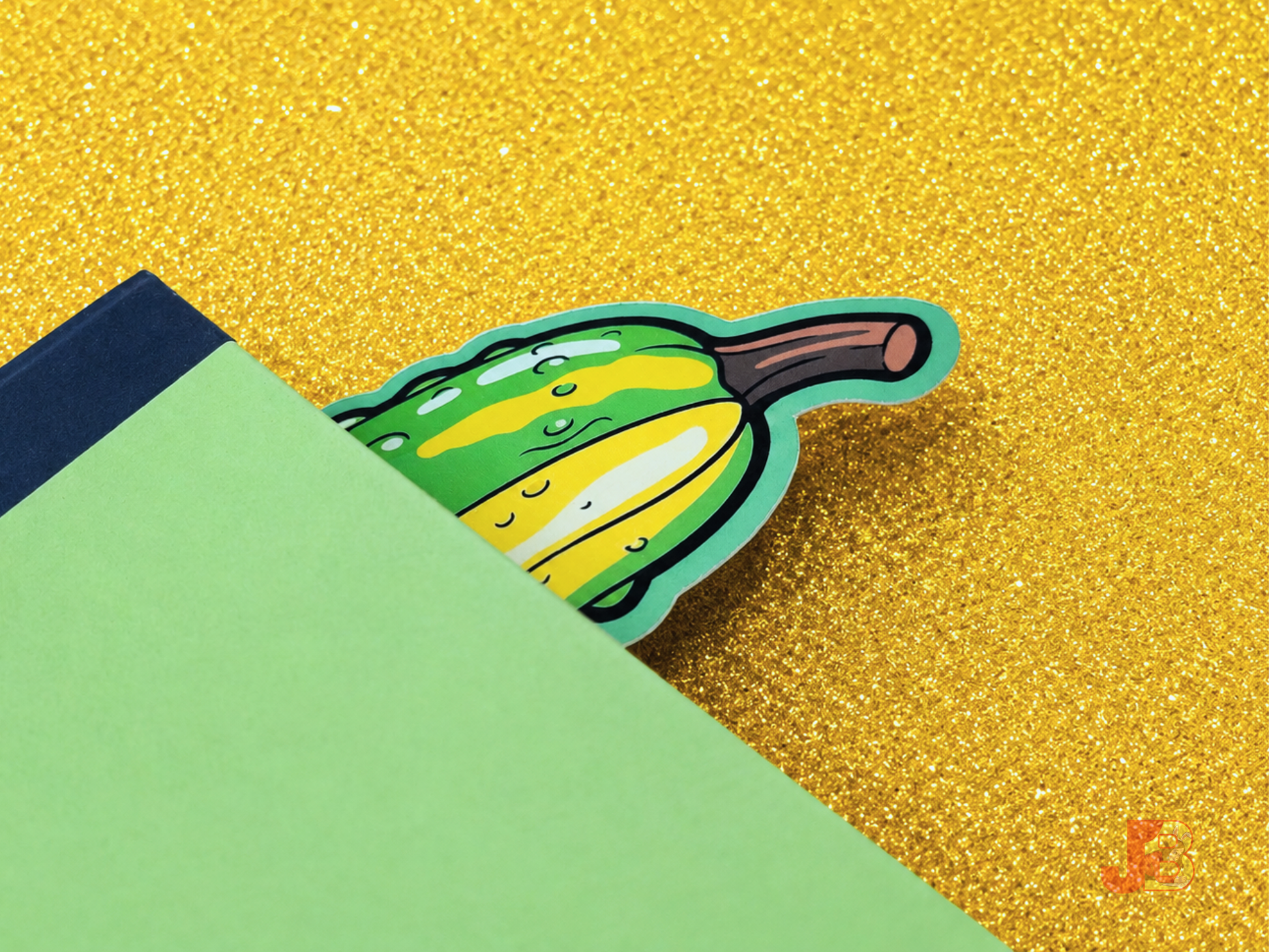 Lifestyle photo of the large 7-inch pickle bookmark tucked inside and peeking out the top of a thick romance hardcover novel.