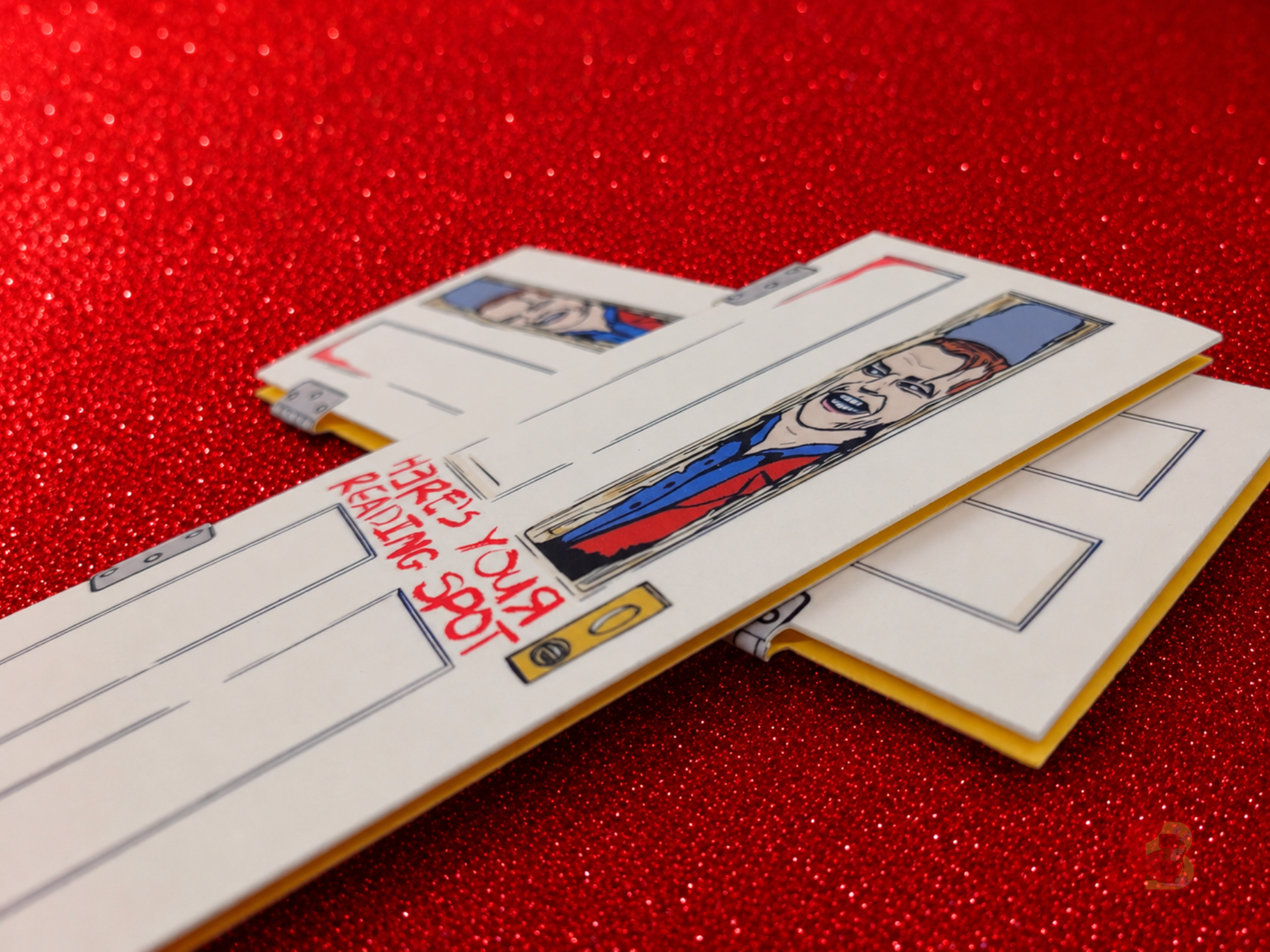Jack Torrance horror magnetic bookmarks laying on top of glitter cardstock.