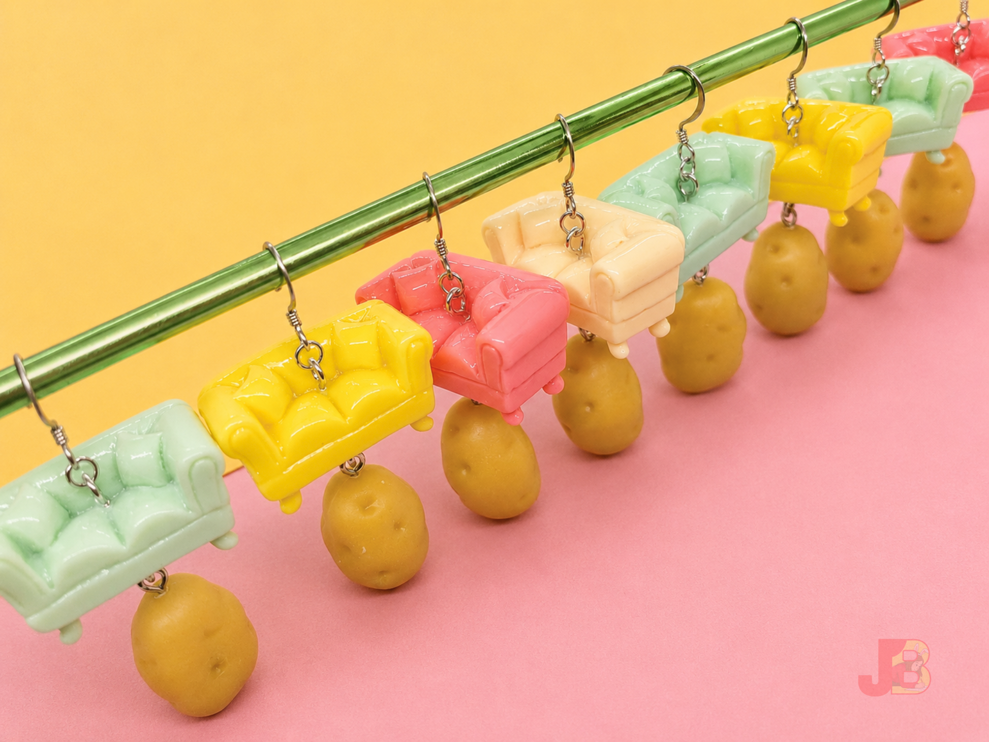 Several pairs of handmade Couch Potato earrings featuring couch charms with miniature potatoes dangling underneath.